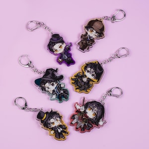 May include: A collection of acrylic keychains featuring anime-style characters in various outfits. Each keychain has a silver-colored metal ring. The characters are depicted with large eyes and detailed clothing, set against a light pink background.