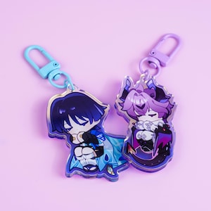 Può includere: Due portachiavi in acrilico con disegni di personaggi dei cartoni animati. Un portachiavi presenta un personaggio con i capelli blu scuro e un abito blu e bianco. L'altro portachiavi ha un personaggio con i capelli viola in un abito viola e nero. Entrambi hanno chiusure in metallo.