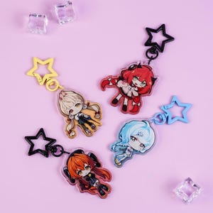 Może przedstawiać: Cztery breloczki do kluczy z postaciami w stylu anime z zapięciami w kształcie gwiazd. Breloczki przedstawiają różne postacie o różnych kolorach włosów, w tym czerwonym, blond i niebieskim. Breloczki znajdują się na jasnofioletowym tle z przezroczystymi, kwadratowymi dekoracjami.