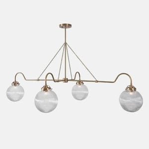 May include: A brass-toned, four-light pendant light fixture. The fixture features four clear, ribbed glass globe shades. The light is suspended from the ceiling by a central rod and chain supports, with curved arms extending to hold the shades.
