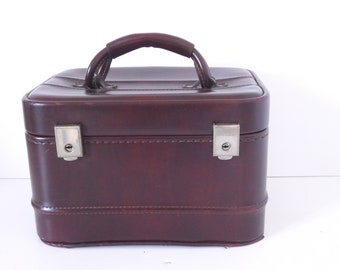 May include: A burgundy leather travel case with a top handle and two silver clasps.