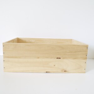 Op de afbeelding: Een natuurlijke houten kist met een rechthoekige vorm en twee niveaus. De kist is gemaakt van onbehandeld hout en heeft een lichtbruine kleur.