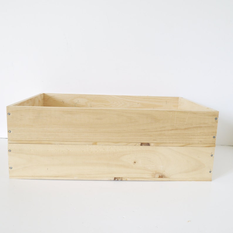 Op de afbeelding: Een natuurlijke houten kist met een rechthoekige vorm en twee niveaus. De kist is gemaakt van onbehandeld hout en heeft een lichtbruine kleur.