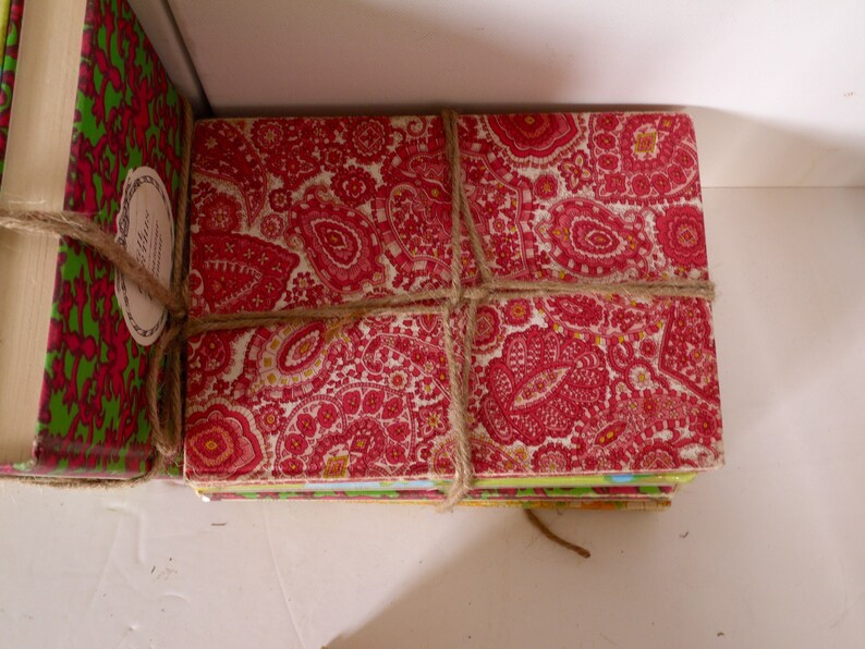 Puede incluir: Una pila de libros envueltos en papel estampado rojo y verde con cuerda marr&oacute;n. Los libros est&aacute;n atados con un lazo.