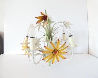 May include: A white metal floral chandelier with four light bulbs. The chandelier features yellow and orange flower accents with green leaves. The light bulbs are clear and have a spiral design.