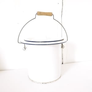 Puede incluir: Cubo de esmalte blanco con borde azul y asa de madera. El cubo tiene un asa de alambre con un agarre de madera.