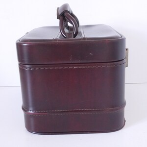 Pode incluir: Uma mala de viagem de couro bord&ocirc; com al&ccedil;a superior e fecho de metal. A mala tem um design costurado e &eacute; feita de um material de alta qualidade.