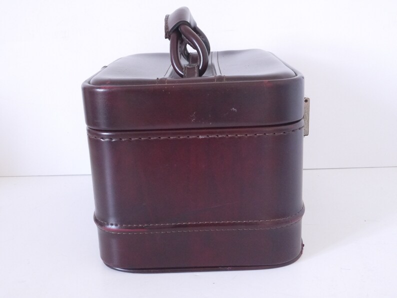 Pode incluir: Uma mala de viagem de couro bord&ocirc; com al&ccedil;a superior e fecho de metal. A mala tem um design costurado e &eacute; feita de um material de alta qualidade.