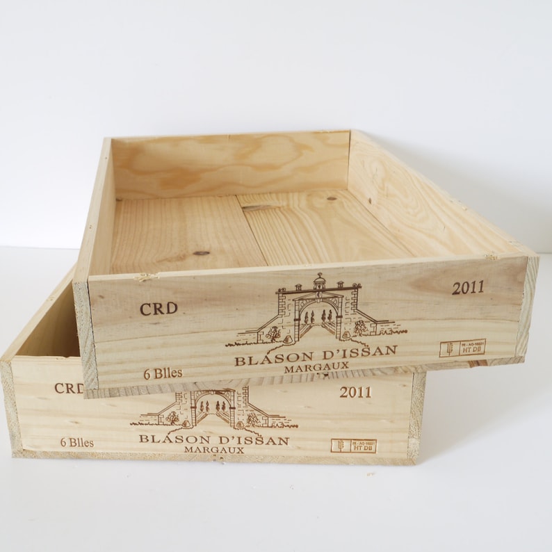 Op de afbeelding: Twee houten wijnkisten op elkaar gestapeld. De bovenste kist heeft de tekst "Blason d'Issan Margaux 2011" en "CRD 6 Billes" erop gedrukt. De onderste kist heeft dezelfde tekst, maar met het jaar 2011.