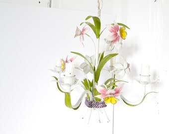 May include: White metal chandelier with pink and yellow flowers. The chandelier has a floral design and is perfect for a vintage or farmhouse style home.
