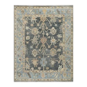 Peut inclure: Tapis rectangulaire avec un champ central gris foncé et une bordure bleu clair. Le tapis présente un motif complexe et symétrique dans des tons beige, bleu clair et pêche. Le design comprend des motifs floraux et géométriques.