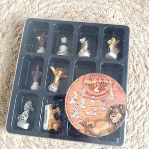 Peut inclure: Un ensemble de figurines miniatures Madagascar 2 dans un plateau en plastique noir. Les figurines représentent des personnages du film d'animation, dont Alex le lion et Marty le zèbre. Une étiquette circulaire avec le logo Madagascar 2 est également incluse.