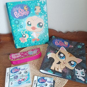 Può includere: Una collezione di articoli Littlest Pet Shop, tra cui due raccoglitori, un astuccio e due cartucce di gioco per Nintendo DS. Gli articoli presentano illustrazioni colorate di animali dei cartoni animati. Su una superficie marrone chiaro.