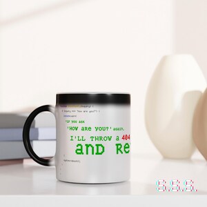 Puede incluir: Una taza de cerámica blanca con asa y borde negros. La taza presenta texto verde que dice "HOW ARE YOU?" y "I'LL THROW a 404 and Re". El diseño de la taza recuerda al código informático.