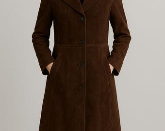 May include: A brown suede coat with a classic design. The coat features a notched collar, three buttons, and two front pockets. The coat is knee-length and has long sleeves.