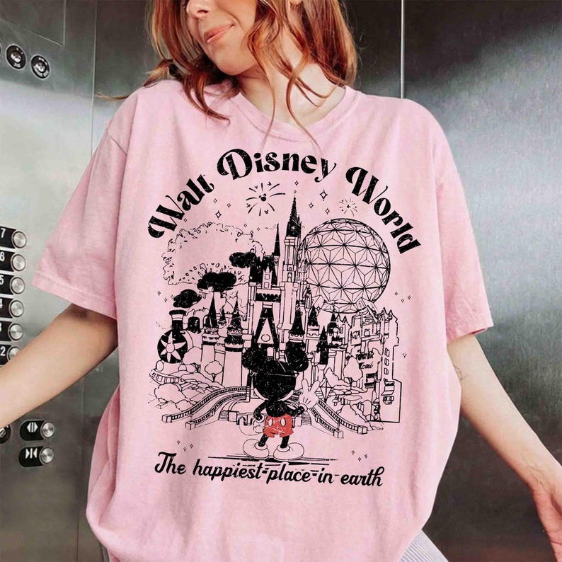 May include: Pink t-shirt with a black and white graphic of a castle, Spaceship Earth, and Mickey Mouse. The text "Walt Disney World" and "The happiest place on earth" are printed on the shirt.
