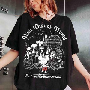May include: Black t-shirt featuring a white graphic of Walt Disney World with Mickey Mouse. The design includes a castle, Spaceship Earth, and the text "The happiest place on earth."