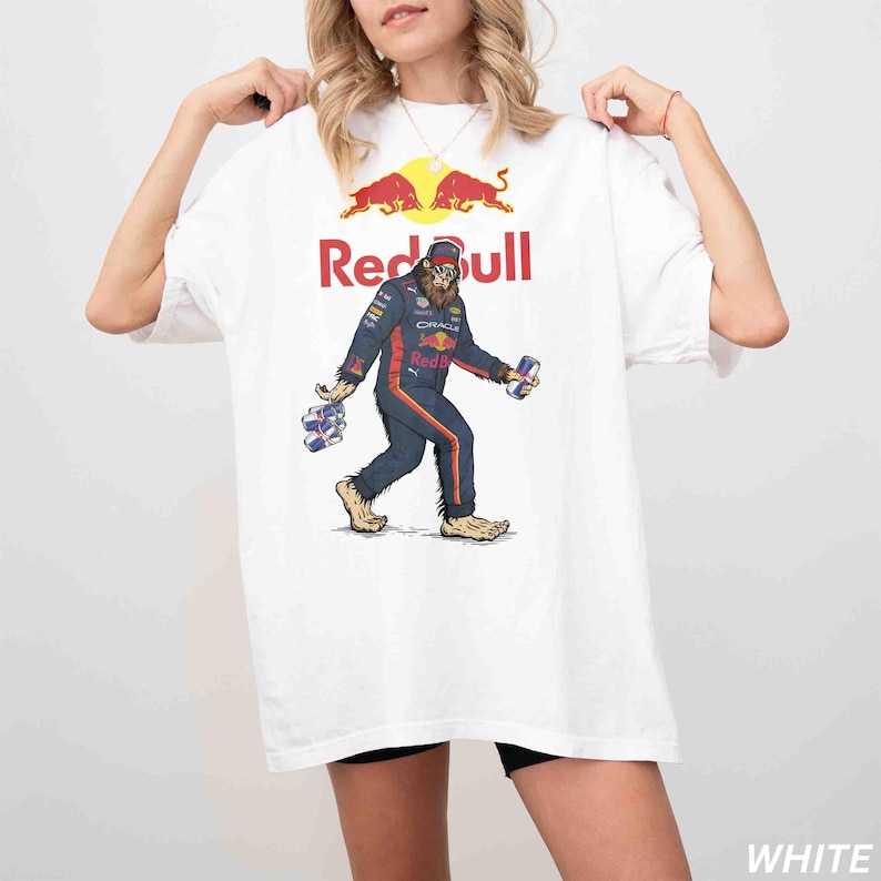 Pu&ograve; includere: T-shirt bianco con un personaggio simile a Bigfoot in tuta da corsa Red Bull, con lattine di energy drink. Il logo e il testo Red Bull sono sopra l'illustrazione. La maglietta ha una vestibilit&agrave; ampia.