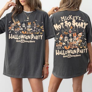 May include: A charcoal gray t-shirt featuring a graphic print of Disney characters in skeleton costumes. The front displays the text Mickey's Not So Scary Halloween Party Walt Disney World. The back shows a larger version of the same graphic.