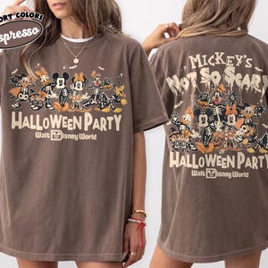 May include: A brown short-sleeve t-shirt featuring a graphic of Disney characters in skeleton costumes. The front displays the text "Halloween Party" and "Walt Disney World." The back features the text "Mickey's Not So Scary Halloween Party."