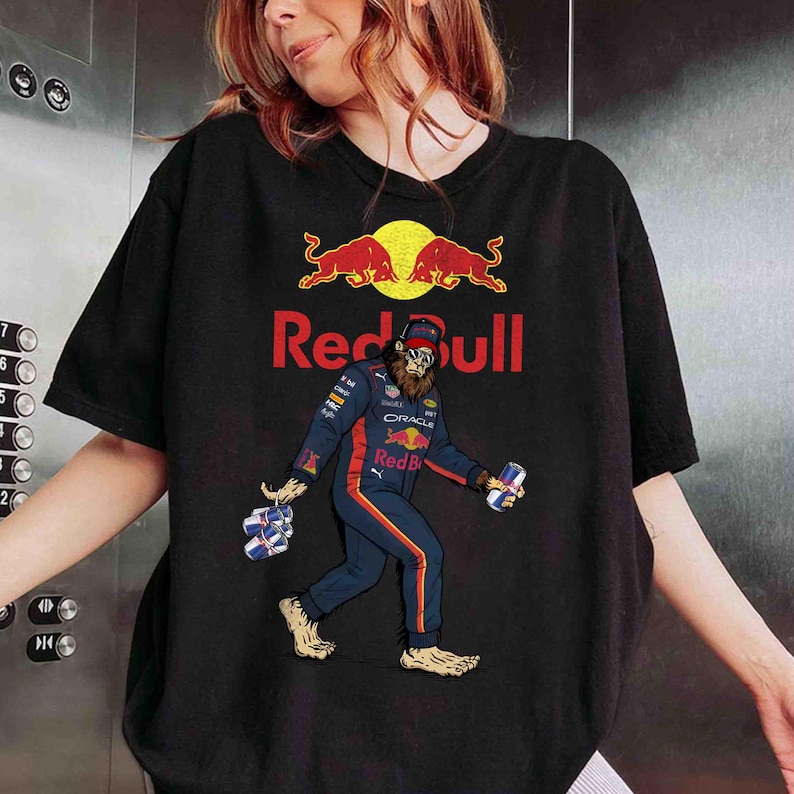 Pu&ograve; includere: T-shirt nera con il logo Red Bull e un personaggio dei cartoni animati di Bigfoot in tuta da corsa, con lattine di Red Bull. Il Bigfoot &egrave; raffigurato mentre cammina, con lattine in ogni mano.