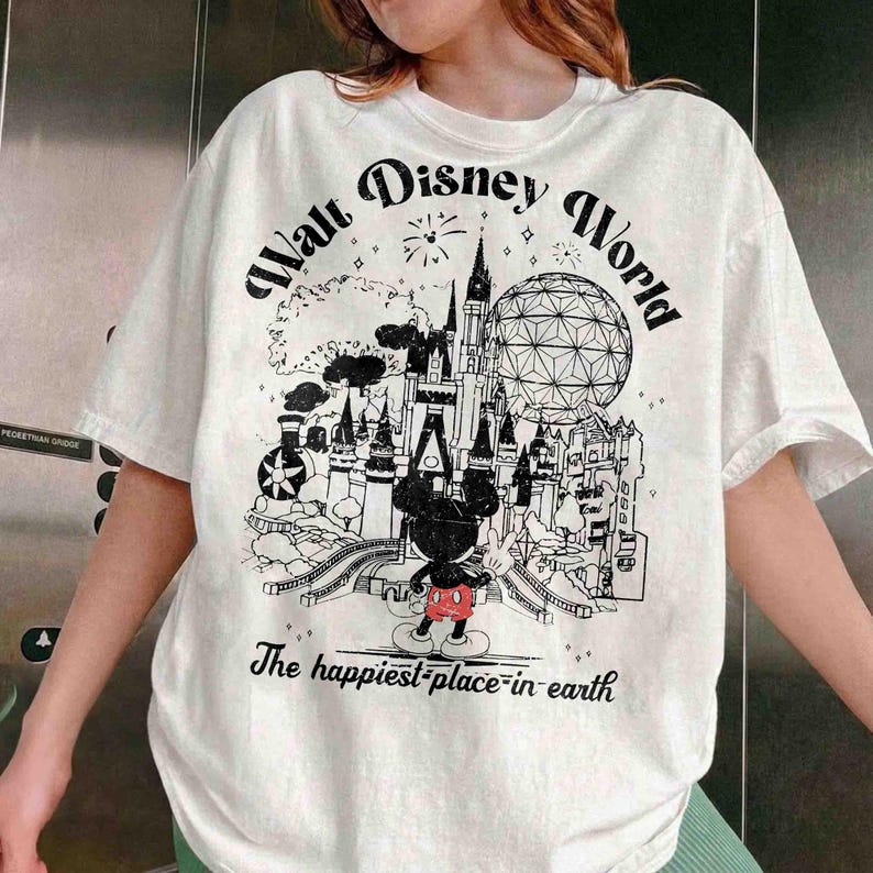 May include: White t-shirt with a black and white graphic of Walt Disney World. The design includes a castle, Spaceship Earth, Mickey Mouse, and the text "Walt Disney World" and "The happiest place on earth."