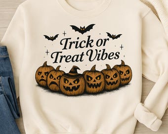 May include: Cream-colored sweatshirt featuring a Halloween design. The graphic includes six carved pumpkins with various expressions, bats, and the text "Trick or Treat Vibes" in a stylized font. A cozy, seasonal apparel item.