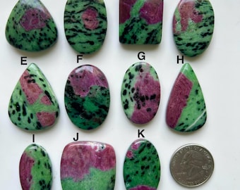 Può includere: Una collezione di gemme di rubino zoisite in varie forme, tra cui ovali, a goccia e rettangolari. Le pietre presentano un mix di colori verde, rosa e nero. Una moneta è inclusa per riferimento alle dimensioni. Adatto per la creazione di gioielli.