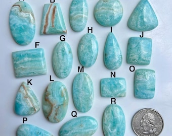 May include: A selection of polished, light blue gemstones in diverse shapes, such as oval, teardrop, and rectangular. The stones display a marbled effect with white and brown veining. A coin is included for size reference.