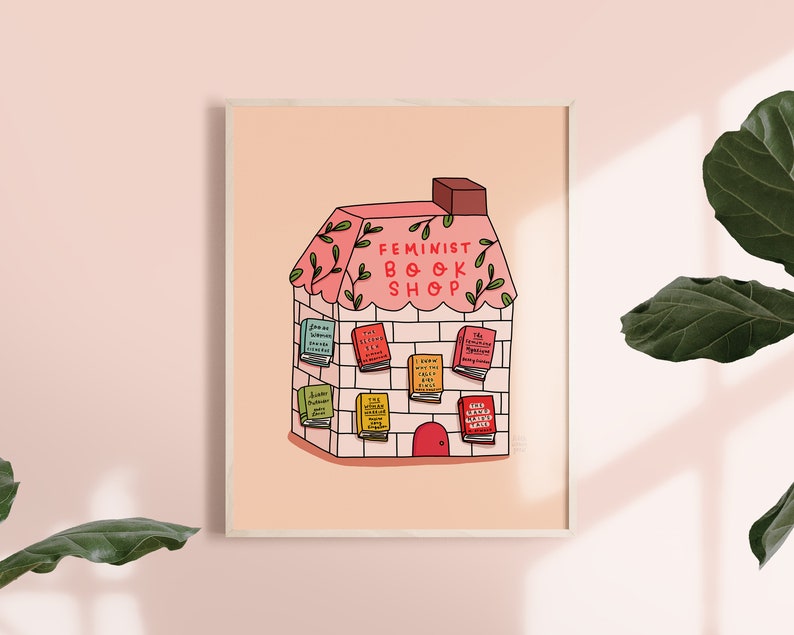 May include: A pink and white illustration of a house with the words "Feminist Book Shop" above the door. The house is decorated with green vines and has books with titles like "I Know Why The Caged Bird Sings" and "The Second Sex" displayed in the windows.