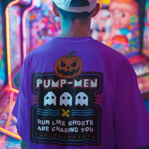 Puede incluir: Una persona con una camiseta morada con un diseño de calabaza y el texto "PUMP-MEN". La camiseta también presenta tres gráficos de fantasmas y la frase "RUN LIKE GHOSTS ARE CHASING YOU". La persona lleva una gorra de béisbol blanca.