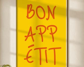 May include: A framed yellow art print with the words "BON APPÉTIT" in orange lettering. The print hangs above a beige sofa with a gray blanket. A modern floor lamp and two round coffee tables complete the room.