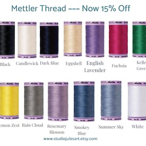 May include: A collection of Mettler thread spools in various colors, including black, white, blue, and green. The image includes text that reads "Mettler Thread ~ Now 15% Off." The website address www.studiojulesart.etsy.com is also visible.