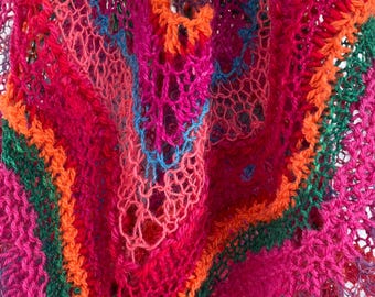 May include: A close-up of a colorful crocheted shawl with a variety of textures and patterns. The shawl is made with a mix of pink, orange, green, and blue yarn.