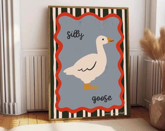 Puede incluir: Un cuadro enmarcado con una ilustración de un ganso blanco con pico y patas naranjas. Las palabras "Silly goose" están escritas en una fuente lúdica. La obra de arte está sobre un fondo azul grisáceo con un borde rojo ondulado.