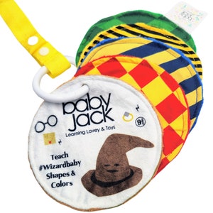 May include: A white and brown baby toy with a sorting hat, glasses, and a ring. The toy is labeled "Baby Jack Learning Lovey & Toys" and "Teach #Wizardbaby Shapes & Colors".