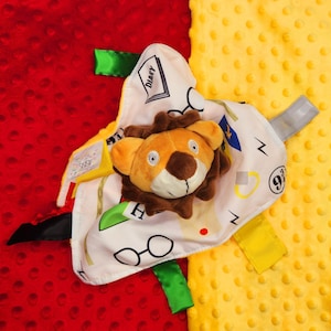 May include: A white and yellow baby blanket with a lion plush toy attached. The blanket has a Harry Potter theme with the words "Diary" and "9 3/4" printed on it.