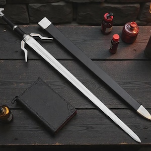May include: A silver sword with a black handle and sheath, resting on a dark wooden surface. The sword has a distinctive design with a guard and a decorative pommel. Other items include a leather-bound book, bottles, and a torch.
