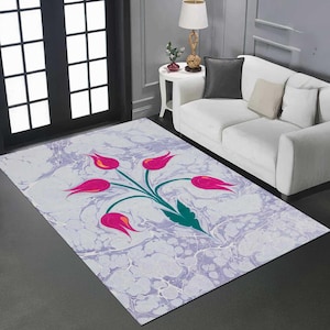 May include: Rectangular area rug with a marbled gray and lavender background. A stylized floral design of pink tulips with green stems and leaves is centered on the rug. The rug is placed on a dark gray floor.