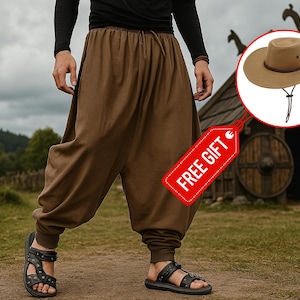 May include: Brown harem pants with a drawstring waist and elastic cuffs. The pants are paired with black sandals. A tan hat with a brown band and chin strap is shown in a circle. A red tag with "FREE GIFT" is attached.