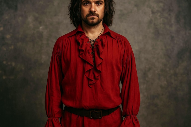 May include: A red long-sleeved shirt with a ruffled front and a black belt. The shirt has a loose fit with flared sleeves. The person in the image has long, dark hair and a beard.