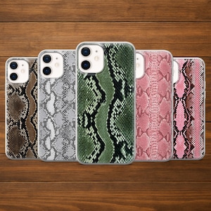 May include: Five mobile phone cases with snake skin patterns in various colours, including brown, grey, green, and pink. The cases are arranged in a row against a wooden background, showcasing the different designs and textures.