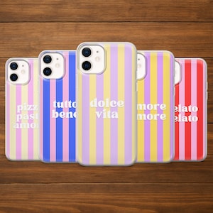 May include: Five phone cases with colorful vertical stripes in pink, yellow, and blue. Each case has a different Italian phrase in white, including "dolce vita" and "more gelato". The cases are on a wooden surface.