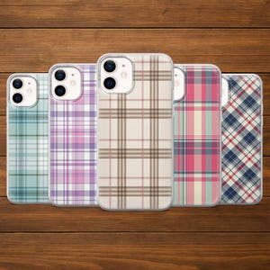 Peut inclure: Cinq coques de téléphone avec des motifs à carreaux de différentes couleurs, dont turquoise, violet, beige, rose et marine. Les coques sont disposées en rangée sur un fond en bois, présentant une gamme de designs.