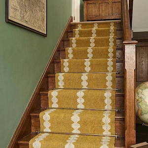Peut inclure: Escalier en bois avec un tapis de course à motifs jaune moutarde et blanc. Les escaliers ont des balustrades et des contremarches en bois foncé. Une carte encadrée de Londres est accrochée au mur vert.