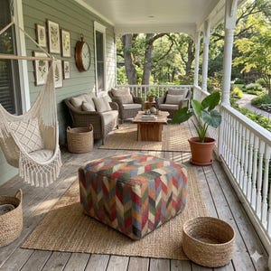 Puede incluir: Un porche cubierto cuenta con una silla colgante de macramé color crema, un sofá de mimbre con cojines beige, dos sillones de mimbre y una mesa de centro de madera. Un puf grande con patrón de chevrón multicolor descansa sobre una alfombra de fibra natural.