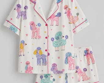 May include: A white pajama set consisting of a short-sleeved button-down shirt and matching shorts. The fabric features a repeating pattern of colorful poodles in shades of pink, purple, yellow, and teal, accented with small hearts and dots.
