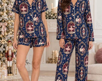 May include: A navy blue pajama set featuring a repeating print of nutcrackers, ballerinas, and swans within ornate gold frames, accented by gold stars. The set includes a button-down collared shirt paired with either matching shorts or long pants.