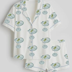 May include: White pajama set with a repeating pattern of blue and green cocktail glasses. The short-sleeved top and shorts have blue trim. The pajama set is made of a soft, lightweight fabric.