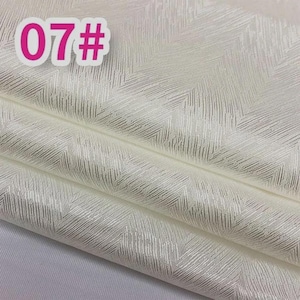 K&ouml;nnte beinhalten: Off-white Stoff mit einem dezenten, strukturierten Fischgr&auml;tmuster. Der Stoff ist gefaltet und zeigt mehrere Schichten. Ein rosa Aufkleber in der oberen linken Ecke zeigt die Nummer "07#".